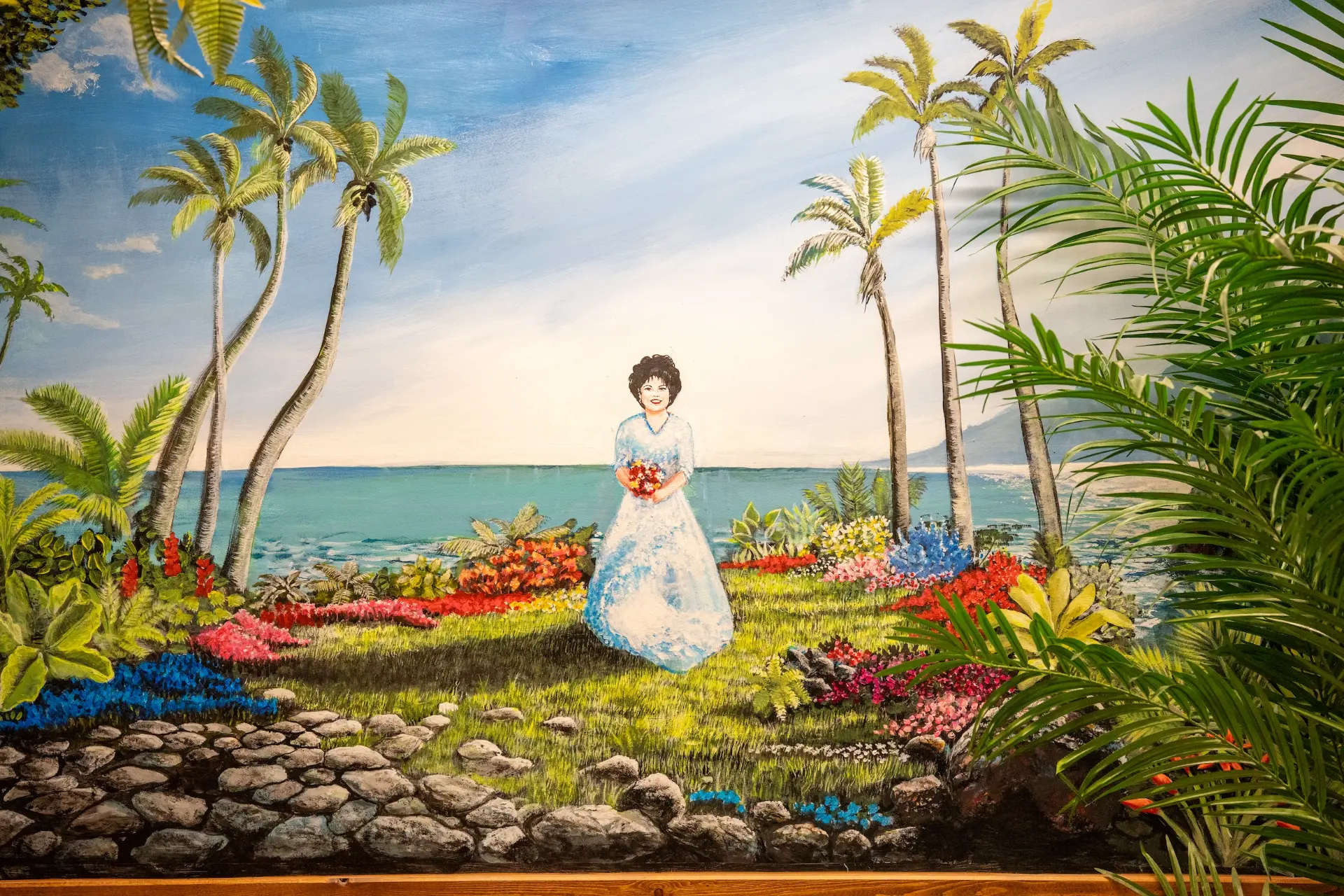 Hand-painted mural of a lady with a bouquet among palms and flowers at ChaChi's