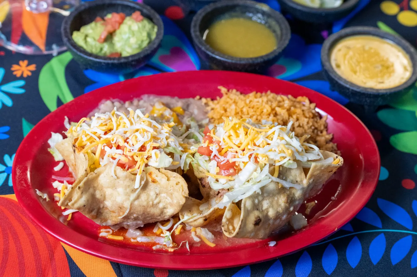 Crispy taco plate with guacamole, green salsa and queso